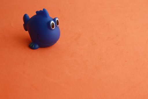 A high angle shot of a cute toy of a blue fish-shaped bathtub on an orange background