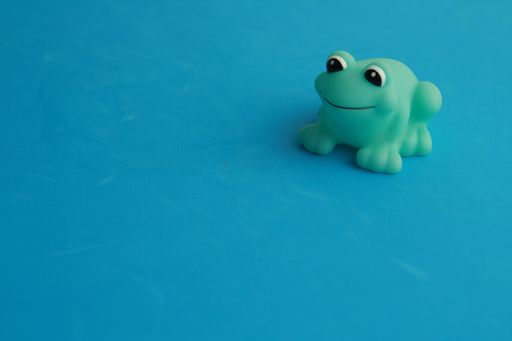 A closeup shot of a green toy frog for a bathtub on a blue background