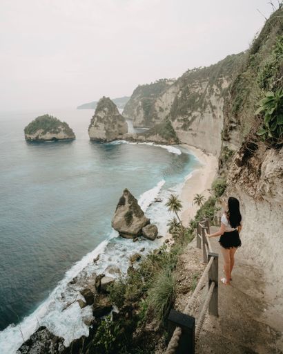A young female enjoying a beautiful view of Diamond Beach on Nusa Penida island in Indonesia