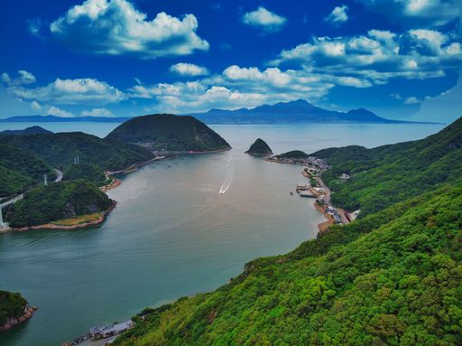 A beautiful aerial view of lush green trees and mountains overlooking a lone boat near Unzen in Kyushu, Japan