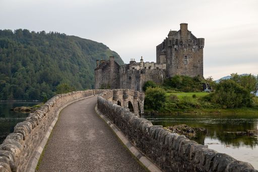 The bridge leading to the Eilean Donan castle above a loch in the forested highlands of Scotland