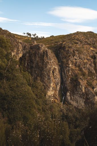 A landscape of high green rocky cliff with plants in Pitoes das Junias Cascata, Portugal