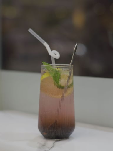 A vertical shot of grape mojito with fresh mint and lime on a white marble surface
