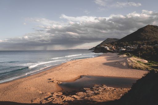 A beautiful shot of a beach with green hills on a cloudy day