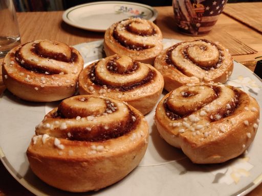 A closeup of a delicious homemade Cinnamon roll buns on white plate on wooden table