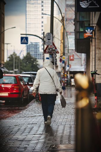 The vertical view from behind of a man walking on the streets of Berlin on a rainy day