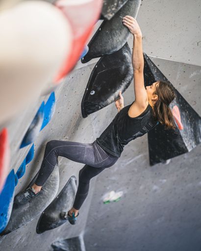 The young fitness woman doing professional bouldering at indoor gym climbing