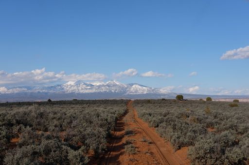 A narrow road through agricultural field to the high mountains