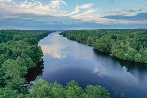 The Pemaquid River surrounded by green, dense forest, aerial