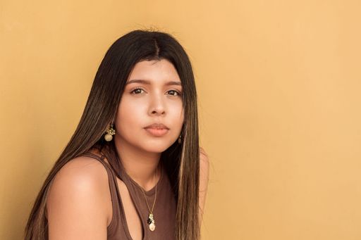 A brunette female looking at camera in yellow background