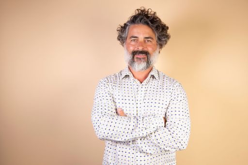 A middle-aged caucasian man dressed casually with arms crossed isolated on a beige background.