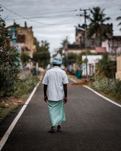 A vertical back view of an Indian male walking in the streets of Karaikudi, Tamil Nadu, India