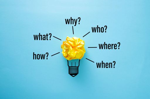A lightbulb with yellow crumpled paper on blue background with the words when, why, what, who, where and how