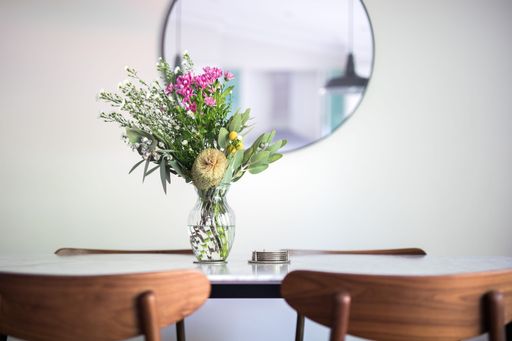 A decorative vase with a floral bouquet on an empty dining table