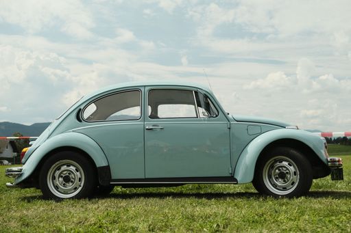 A Blue Volkswagen Beatle parked on grass with blue and cloudy sky background in Spielberg, Austria
