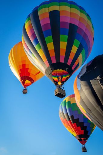 A vertical shot of hot air balloons over a background of a blue sky