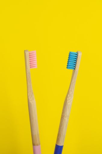 A close up shot of wooden pink and blue toothbrushes representing a couple