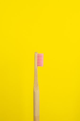 A close up shot of a wooden pink toothbrush