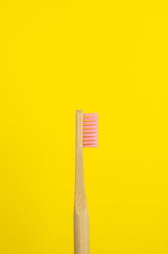 A close up shot of a wooden pink toothbrush