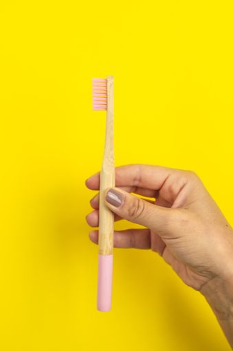 A close up shot of a wooden pink toothbrush