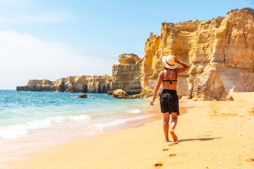 A Caucasian female with a hat on the beach at Praia da Coelha, Algarve, Albufeira. Portugal