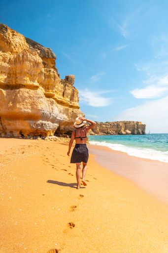 A Caucasian female with a hat on the beach at Praia da Coelha, Algarve, Albufeira. Portugal