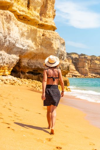 A Caucasian female with a hat on the beach at Praia da Coelha, Algarve, Albufeira. Portugal
