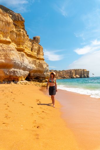 A Caucasian female with a hat on the beach at Praia da Coelha, Algarve, Albufeira. Portugal