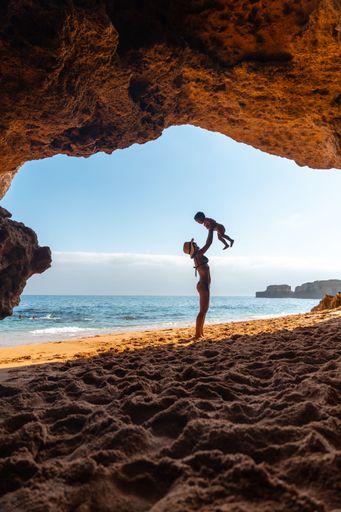 A Caucasian female with her son in the natural cave in the Algarve at Praia da Coelha, Albufeira