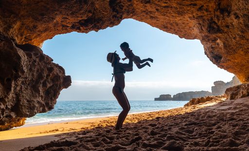 A Caucasian female with her son in the natural cave in the Algarve at Praia da Coelha, Albufeira