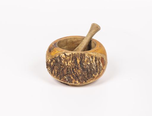 A closeup shot of a handmade wooden mortar with a pestle