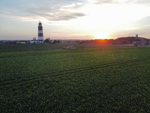 A lighthouse on the coast of the sea during sunset