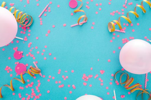 A top view of confetti and balloons on a blue background with space for text in the center