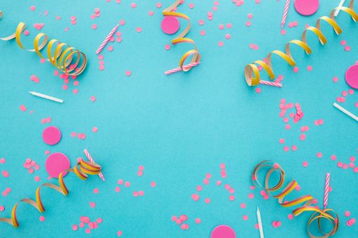 A top view of confetti on a blue background with space for text in the center