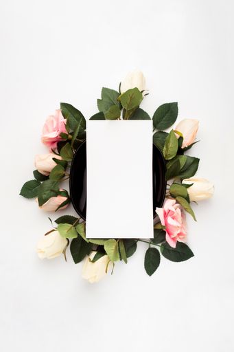 A vertical shot of a blank piece of paper surrounded by roses