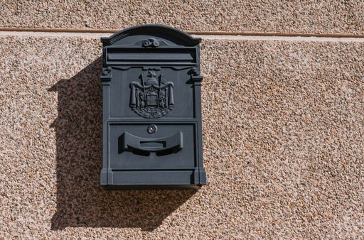 A closeup of a metal mailbox attached to the wall during daylight