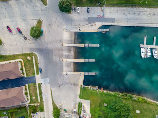 An aerial top view of a harbor surrounded by houses, grass and roads