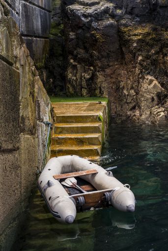 A vertical shot of a boat on the lake near the stairs surrounded by beautiful rock formations