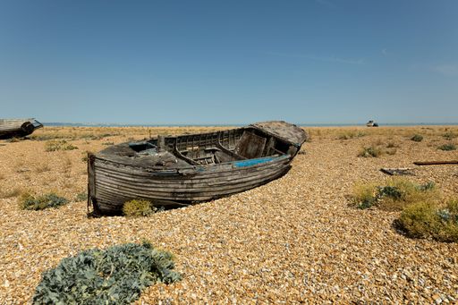 An old wooden fishing boat isolated in the desert under the clear sky