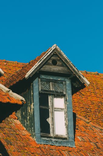A vertical shot of an old dormer on the roof of a building