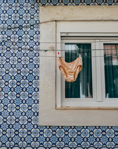 A vertical shot of underwear hanging on a rope in front of a window