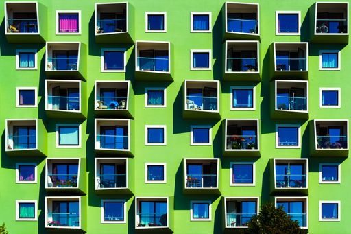 A happy green modern building with different kinds of plants on balconies