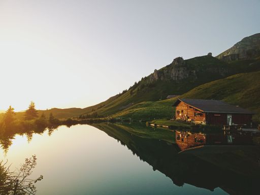 Landscape of the beautiful swiss lake with a wooden house close to it and a mountain behind it while the sunset. mountain and a house are reflecting