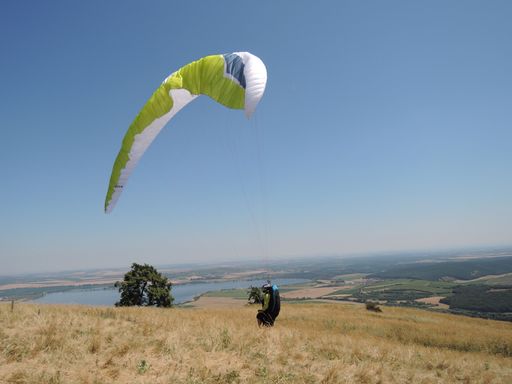 A person paragliding in a free fly in Europe in Alps mountains with blue sky in the background