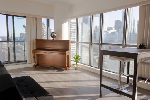 A modern minimalistic room with a piano in it and big windows under the sunlight