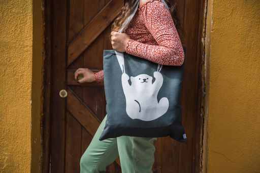 A faceless woman posing against wooden door with bear tote bag on the shoulder