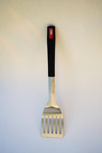 A vertical shot of kitchen utensils on a white wall