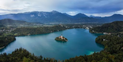 An aerial shot of the church on Bled island with its reflection on Bled lake surface