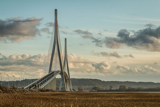 A curvy cable-stayed bridge in a grassy field under the beautiful cloudy sky