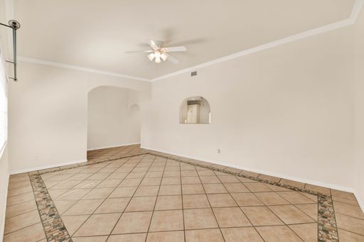 A large empty room with white walls and tiled floors in a brand new house